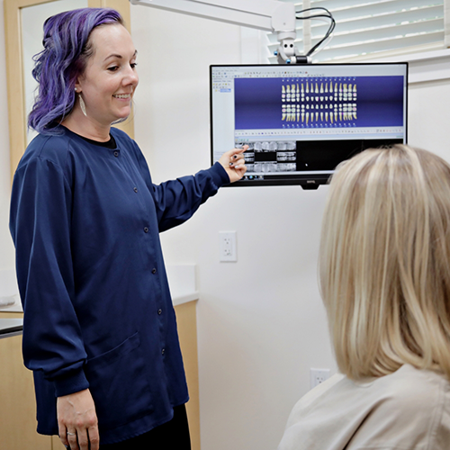 Dental team member showing patient digital renders of teeth