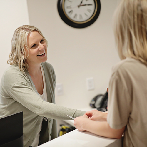 Woman smiling and talking to team member at desk