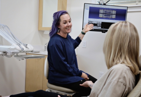 Female dental team member sitting and smiling at dental patient