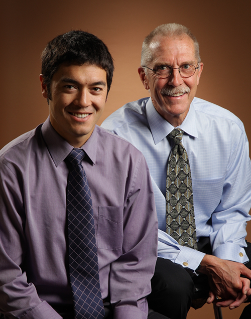 Two men with ties sitting next to each other