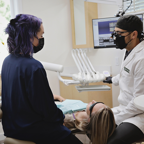 Patient lying down between dentist and dental team member