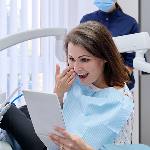 Female dental patient checking smile in mirror