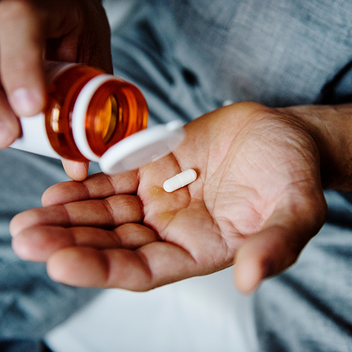 Person holding bottle and pill for sedation dentistry in Langley