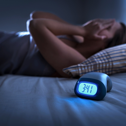 Alarm clock and woman lying awake in bed